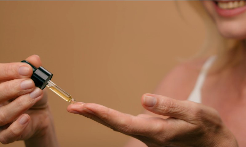 Žena pipetom nanosi ulje na svoj dlan