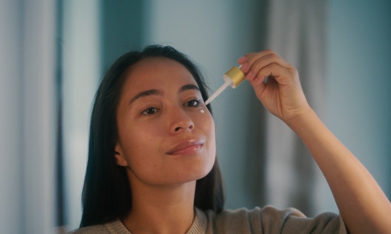Žena nanosi ulje za kožu pipetom na lice