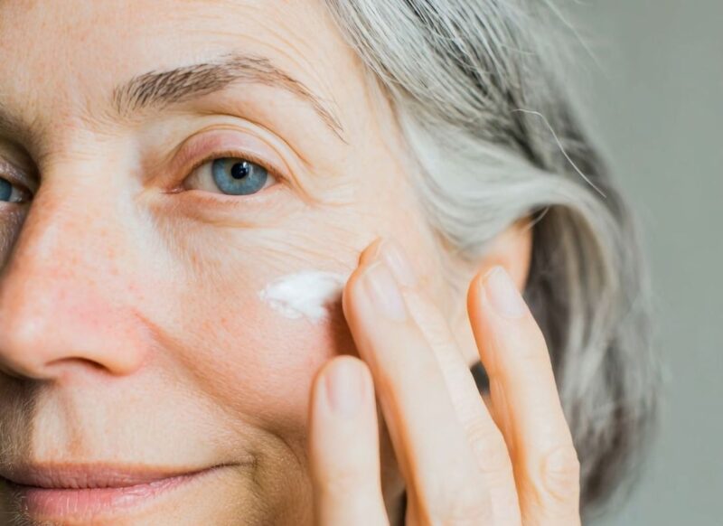 starija žena nanosi kremu na lice