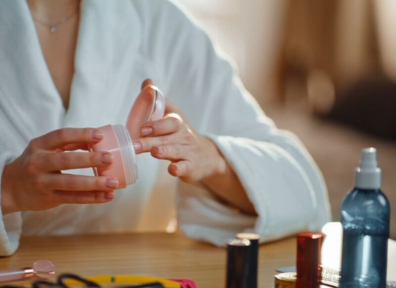 prikaz kozmetike kod devojke na stolu i krema u njenim rukama