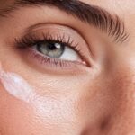 Krupan kadar oka i obraza žene dok nanosi kremu za hidrataciju i hranjenje kože