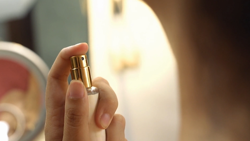 Žena nanosi mirisnu vodicu na vrat