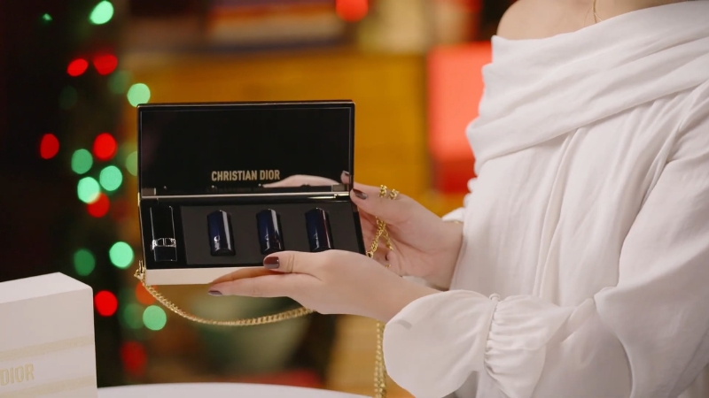 Žena u beloj bluzi drži otvoren Christian Dior poklon set