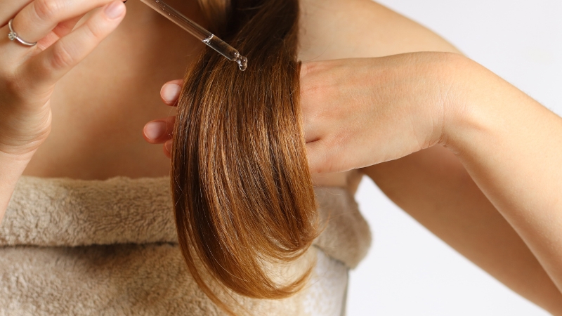 Žena pipetom nanosi serum na kosu