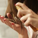 Žena nanosi serum na krajeve kose dok drži bočicu sa pumpicom u ruci