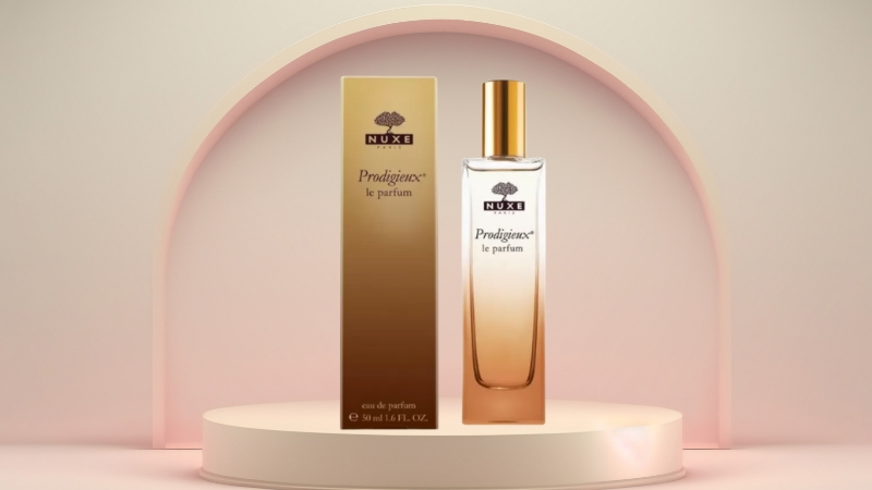 Bočica i kutija Prodigieux le parfum stoje na postolju sa blagim roze pozadinskim lukom