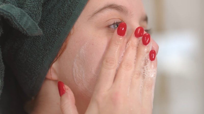 Žena čisti lice penastom umivalicom