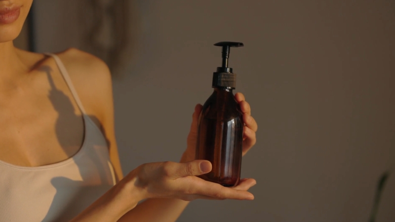 Žena drži bočicu proizvoda za negu kose